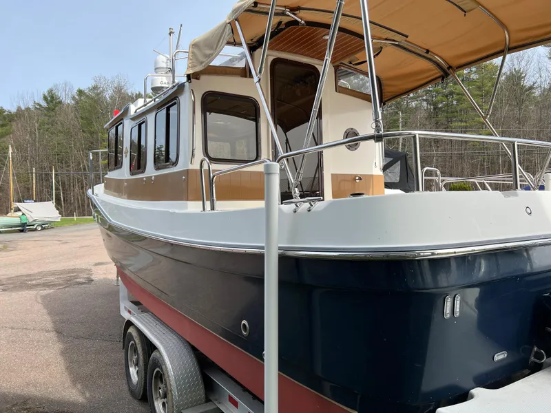 Slide: The Image of 2013 Ranger Tugs R-27 boat on trailer, parked outdoors with trees in background. - 14