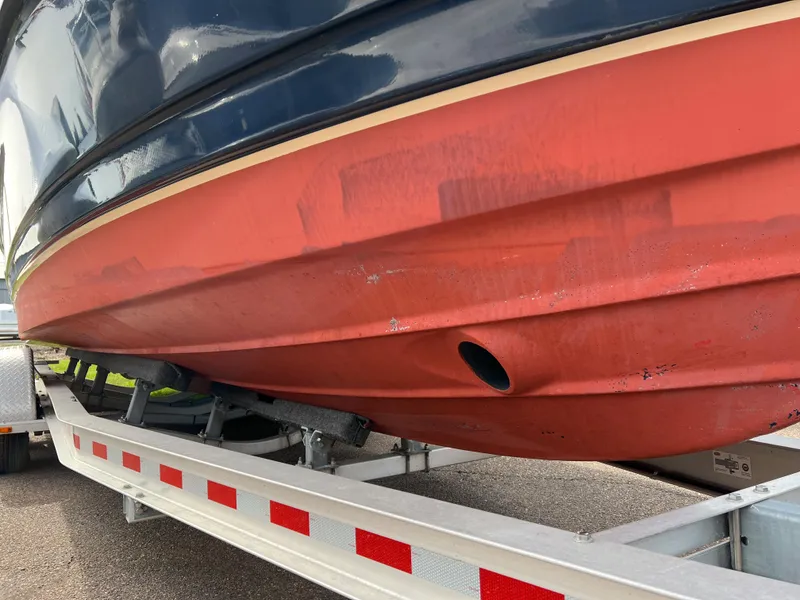 Slide: The Image of 2013 Ranger Tugs R-27 boat hull on trailer, showcasing red and blue exterior. - 18