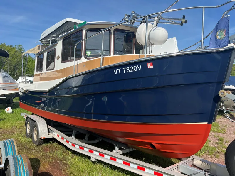 Slide: The Image of 2013 Ranger Tugs R-27 boat on trailer, blue and red hull, parked outdoors. - 4