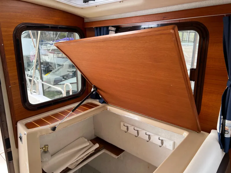 Slide: The Image of 2013 Ranger Tugs R-27 interior with wooden storage compartment and window view. - 42