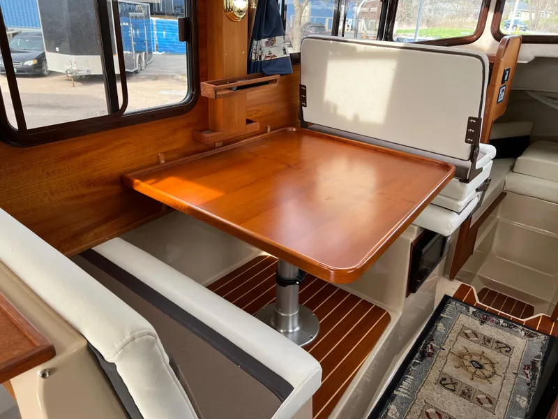 Slide: The Image of Interior of 2013 Ranger Tugs R-27 with wooden table and seating area. - 43
