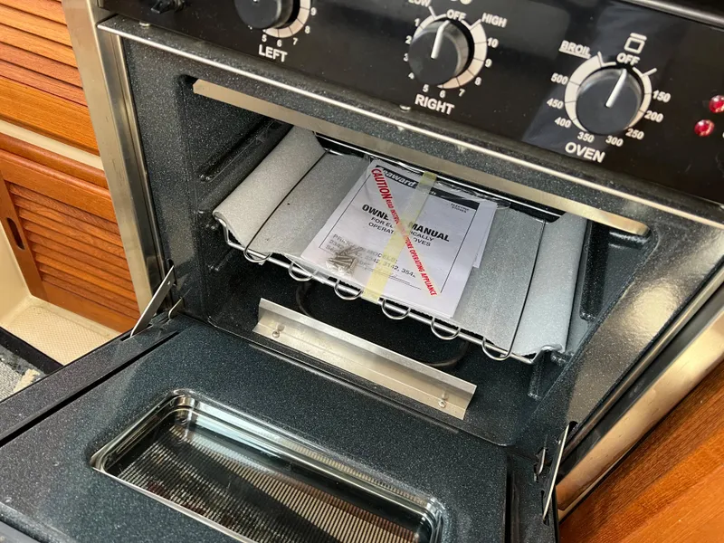 Slide: The Image of Ranger Tugs R-27 2013 oven with manual inside, showcasing control knobs and interior. - 45