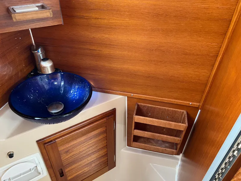 Slide: The Image of 2013 Ranger Tugs R-27 bathroom with blue glass sink and wooden cabinetry. - 52