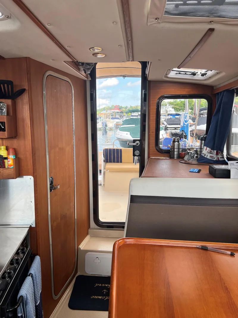 Slide: The Image of Interior of 2013 Ranger Tugs R-27 boat, featuring wood paneling and a view of the marina. - 6