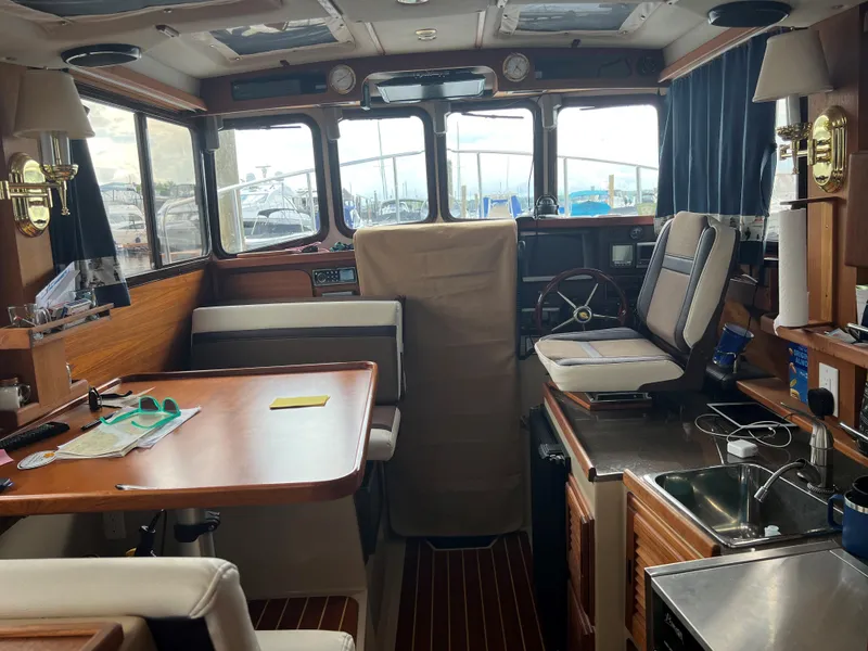 Slide: The Image of Interior of a 2013 Ranger Tugs R-27 boat, featuring a cozy cabin with seating and kitchenette. - 7