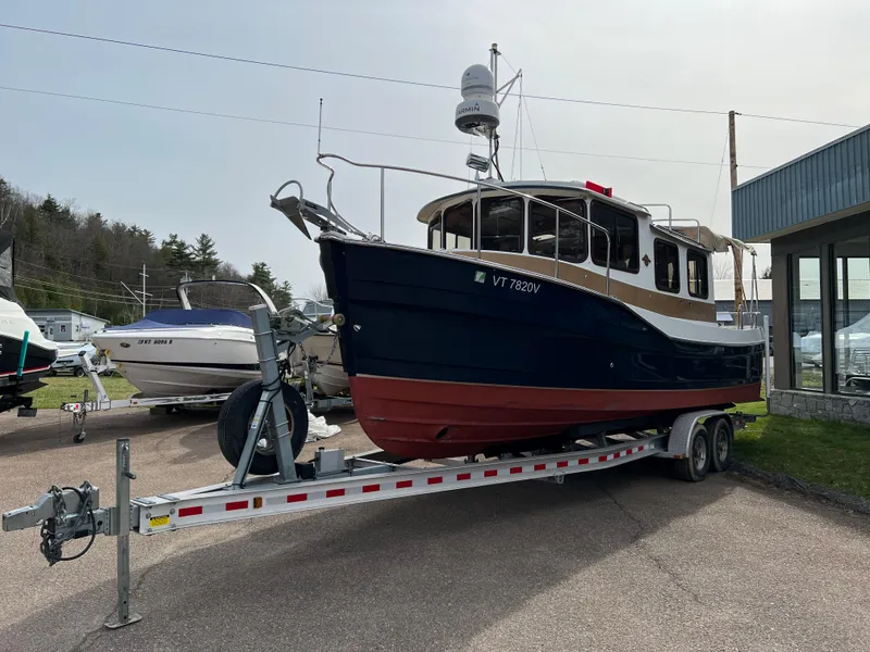 Slide: The Image of 2013 Ranger Tugs R-27 boat on trailer, parked outdoors near other boats. - 8