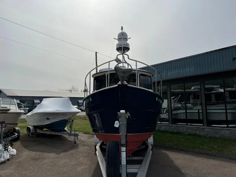 Slide: The Image of 2013 Ranger Tugs R-27 boat on trailer, parked outdoors near a building. - 9