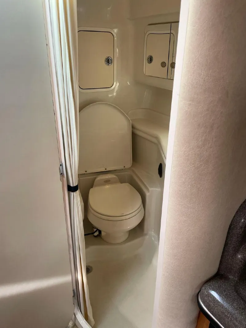 Slide: The Image of 2005 Sea Ray 320 Sundancer boat bathroom with toilet and storage cabinets. - 14