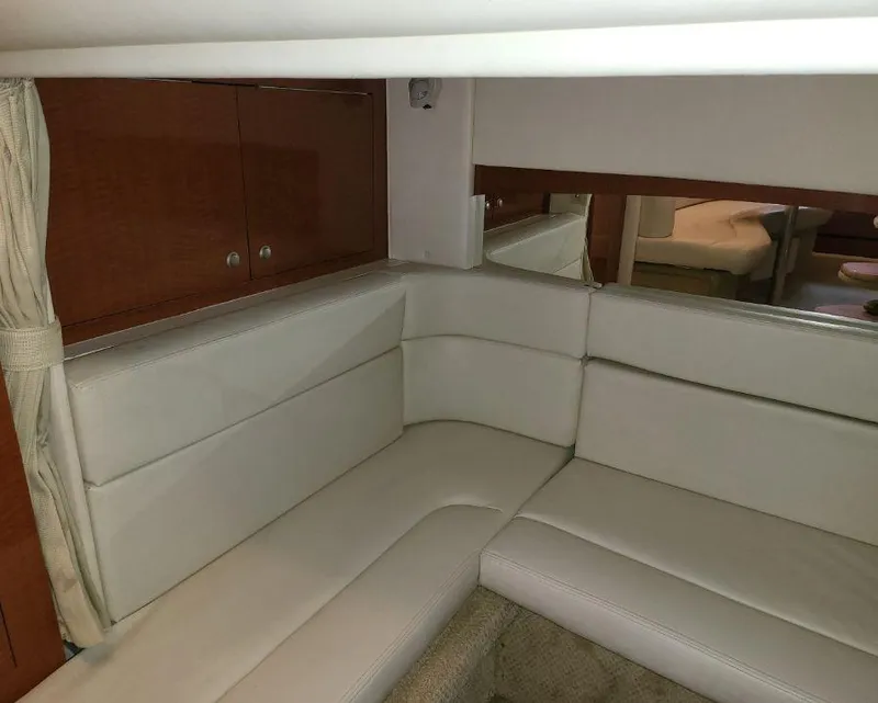 Slide: The Image of 2005 Sea Ray 320 Sundancer cabin interior with white leather seating and wooden cabinets. - 22