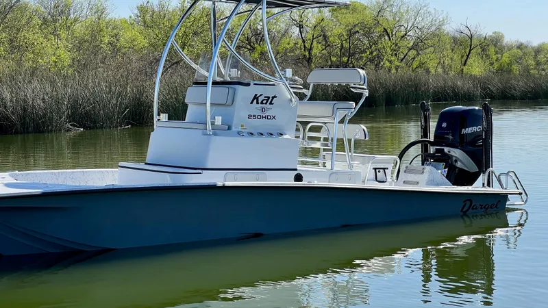 Slide: The Image of 2023 Dargel KAT 250 DX boat on calm water with lush greenery in the background. - 26