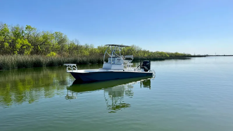 Slide: The Image of 2023 Dargel KAT 250 DX boat on calm water near a lush shoreline. - 27