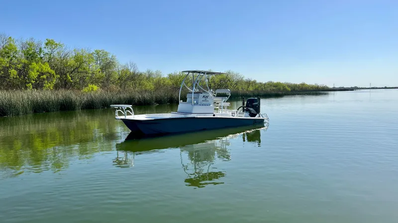Slide: The Image of 2023 Dargel KAT 250 DX boat on calm water near a lush shoreline. - 28