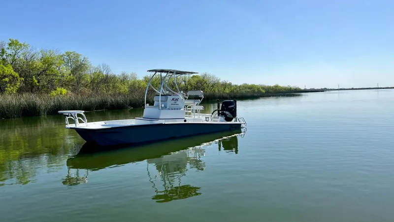 Slide: The Image of 2023 Dargel KAT 250 DX boat on calm water with trees in the background. - 29