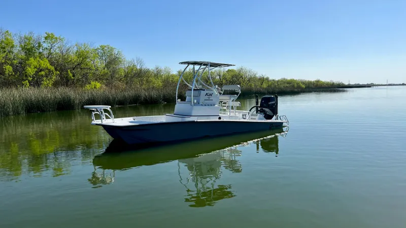 Slide: The Image of 2023 Dargel KAT 250 DX boat on calm water with lush greenery in the background. - 30