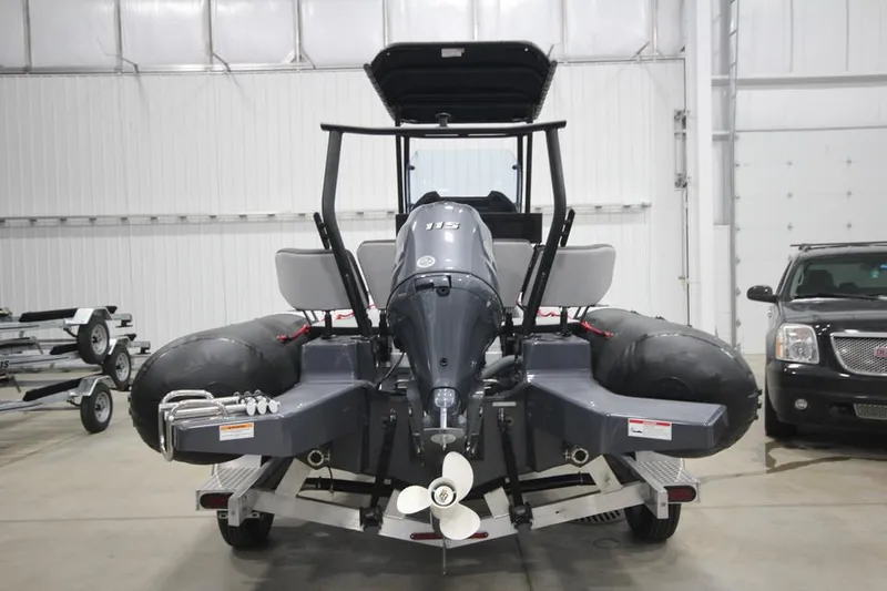 Slide: The Image of 2023 Zodiac Open 5.5 PVC T-Top 115hp boat in stock, rear view in a warehouse. - 2