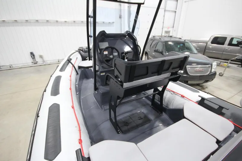 Slide: The Image of 2023 Zodiac Open 5.5 PVC T-Top 115hp boat interior in stock, featuring seating and control console. - 5