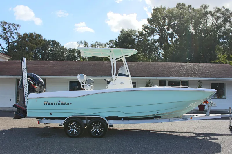 Slide: The Image of 2023 NauticStar 231 Hybrid boat on trailer, parked outdoors. - 2