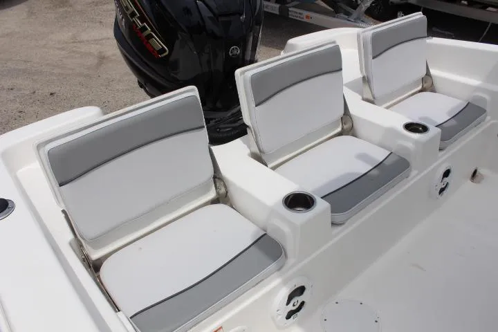 Slide: The Image of 2023 NauticStar 231 Hybrid boat with three cushioned seats and a black outboard motor. - 8