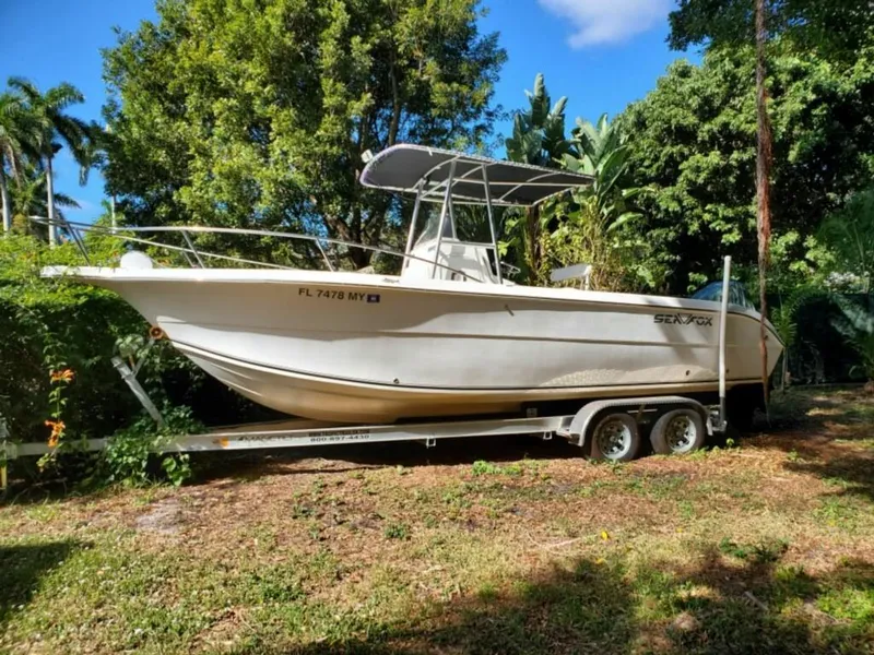 Slide: The Image of 2006 Sea Fox 256 Center Console boat on a trailer in a lush, green yard. - 6