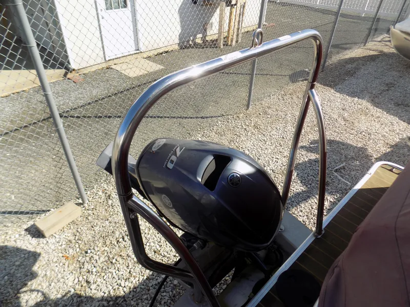 Slide: The Image of 2013 Sweetwater 2086 boat with Yamaha outboard motor, parked on gravel near a chain-link fence. - 7