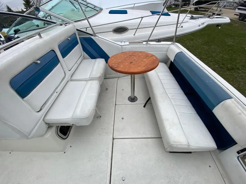 Slide: The Image of 1989 Sea Ray Sundancer boat interior with white and blue seating and a wooden table. - 11