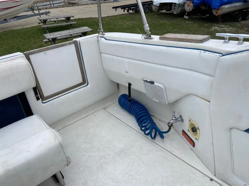Slide: The Image of 1989 Sea Ray Sundancer boat interior with white seating and blue coiled hose. - 12