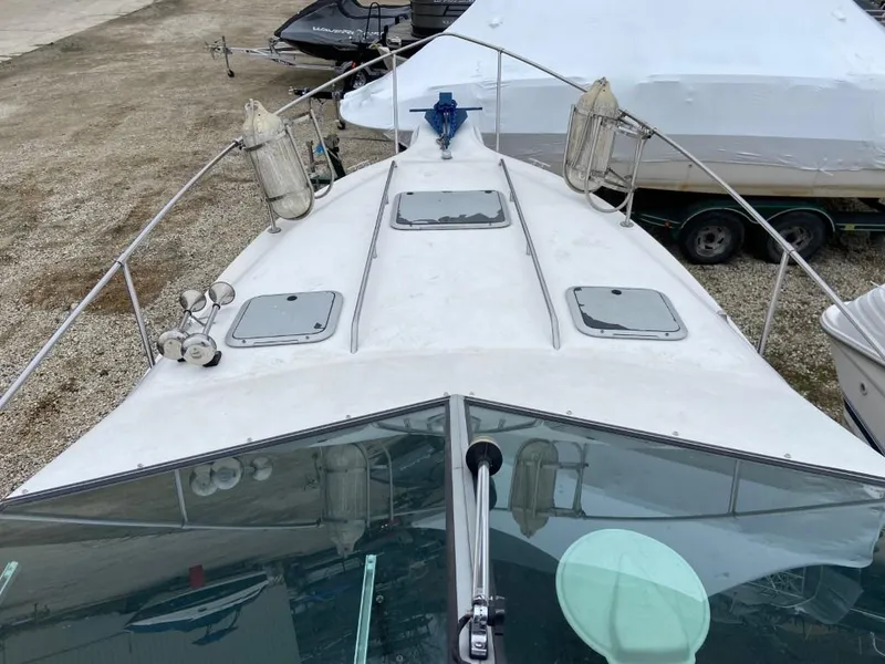 Slide: The Image of 1989 Sea Ray Sundancer boat deck with hatches and railings, docked on gravel. - 7