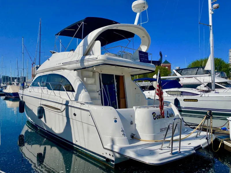 Slide: The Image of A white 2004 Meridian 411 Sedan yacht docked in a marina. It features an open upper deck and an American flag. - 21