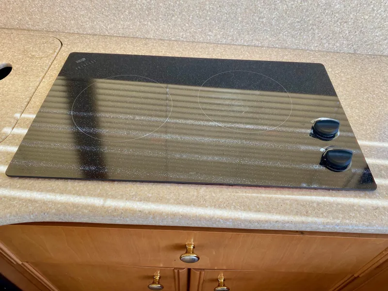 Slide: The Image of A sleek black cooktop with two knobs on a kitchen countertop. - 16