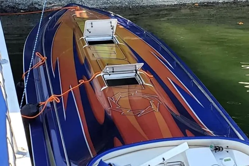 Slide: The Image of 1999 Fountain 47 Lightning speedboat with vibrant orange and blue design docked in water. - 5