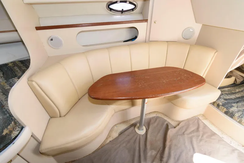 Slide: The Image of 2000 Cruisers Yachts 2870 Express interior seating area with wooden table. - 7