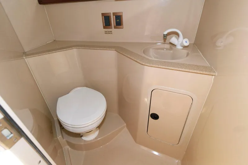 Slide: The Image of 2000 Cruisers Yachts 2870 Express bathroom with toilet, sink, and storage cabinet. - 11