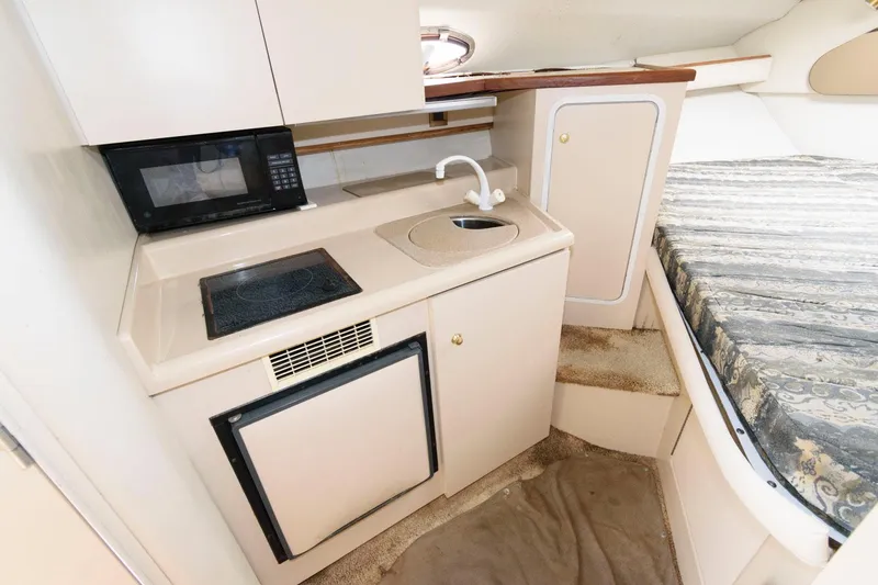 Slide: The Image of Compact kitchen area in 2000 Cruisers Yachts 2870 Express with sink, stove, and microwave. - 9