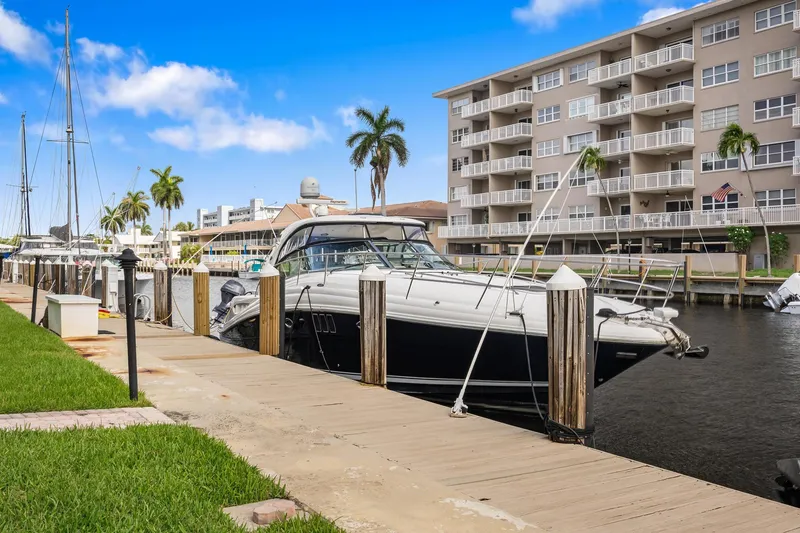 Slide: The Image of 2008 Sea Ray 44 Sundancer docked near waterfront apartments, under a clear blue sky. - 4
