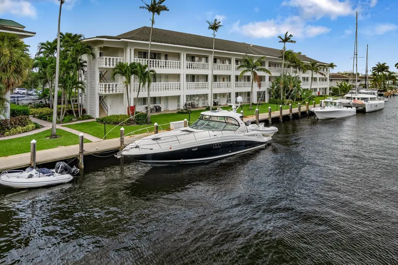 Slide: The Image of 2008 Sea Ray 44 Sundancer yacht docked by waterfront building with palm trees. - 45