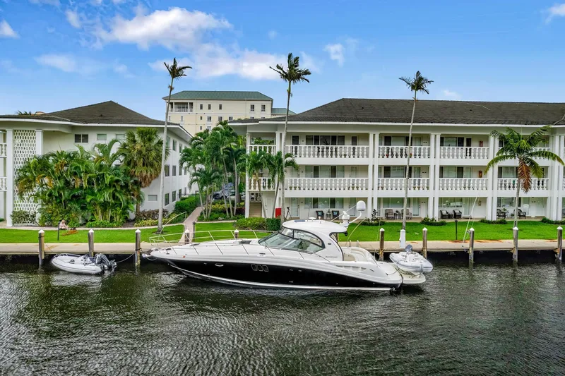 Slide: The Image of 2008 Sea Ray 44 Sundancer yacht docked by waterfront apartments with palm trees. - 47