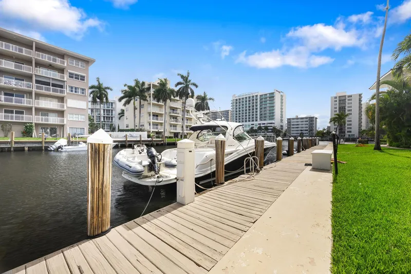 Slide: The Image of 2008 Sea Ray 44 Sundancer docked at a marina with waterfront buildings and palm trees. - 5