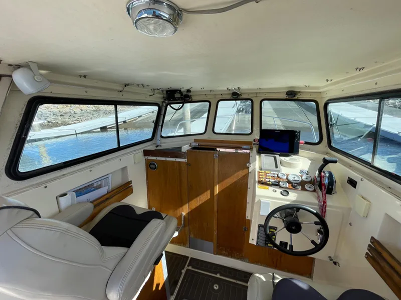 Slide: The Image of 1984 Farallon 25 Whaleback boat interior with steering wheel, control panel, and seating. - 10
