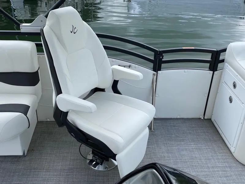 Slide: The Image of Captain's chair on 2023 JC Neptoon Sport 23TT pontoon boat, white upholstery, lake background. - 12