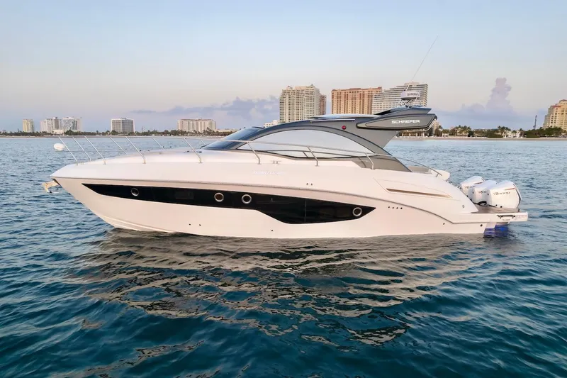 Slide: The Image of 2025 Schaefer 400 Sport yacht on calm water with city skyline backdrop. - 7