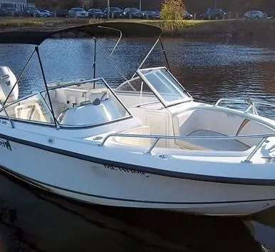 Slide: The Image of 2002 Mako 195 Dual Console boat on calm water, featuring a sleek design and canopy. - 0