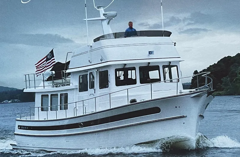 Slide: The Image of 2025 Nordic Tug 49 cruising on a calm lake with an American flag. - 14
