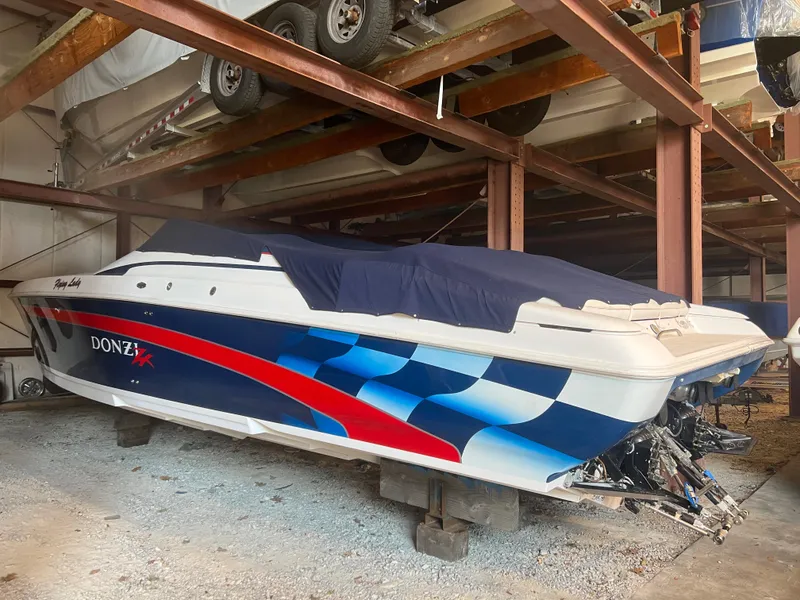 Slide: The Image of 2001 Donzi 38 ZX speedboat in storage, featuring a vibrant blue and red design. - 3