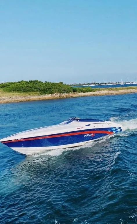 Slide: The Image of 2001 Donzi 38 ZX speedboat cruising on blue water near a green shoreline. - 8
