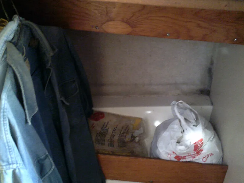 Slide: The Image of Small storage area in a 1980 Bertram 28 Flybridge Cruiser with hanging clothes and bags. - 12