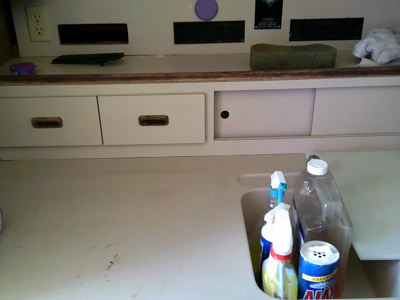 Slide: The Image of Interior of 1980 Bertram 28 Flybridge Cruiser with cleaning supplies on counter. - 13