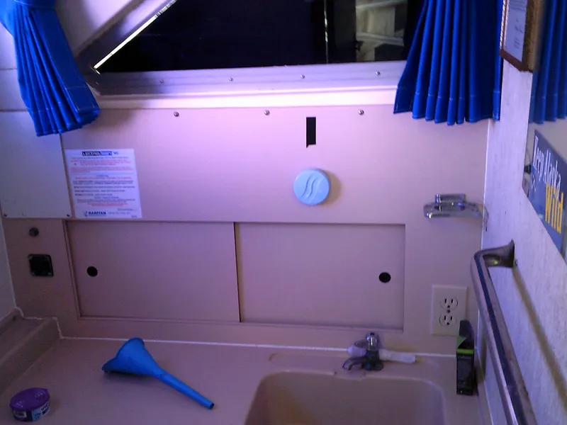 Slide: The Image of Interior of 1980 Bertram 28 Flybridge Cruiser with sink and blue curtains. - 14