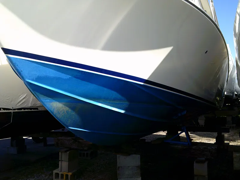 Slide: The Image of 1980 Bertram 28 Flybridge Cruiser hull on blocks, blue and white paint. - 30
