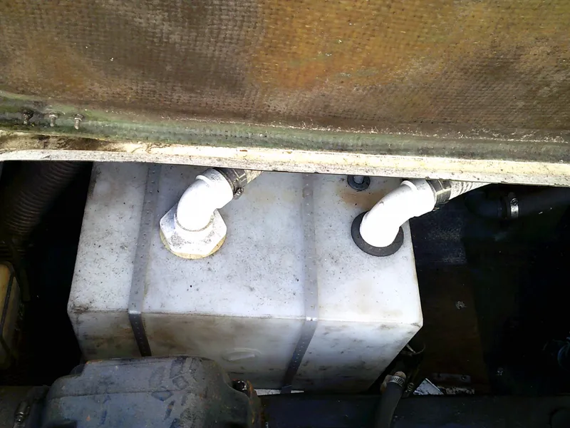 Slide: The Image of 1980 Bertram 28 Flybridge Cruiser engine compartment with white plastic tank and pipes. - 5