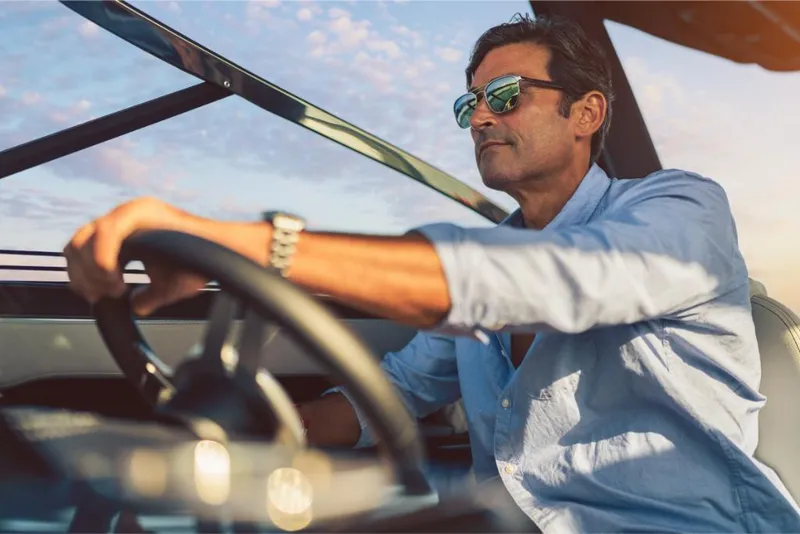 Slide: The Image of Man driving 2023 Sea Ray SLX 260 boat, wearing sunglasses, enjoying a sunny day. - 16